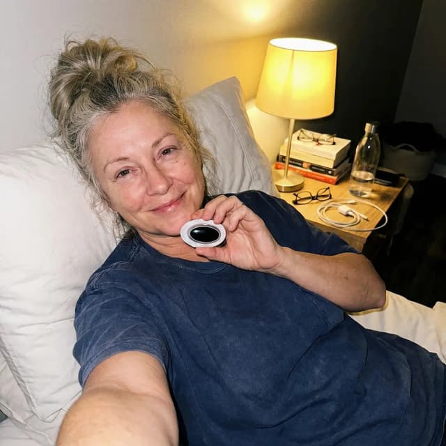 SleepEase Pro customer smiling in bed with the device case